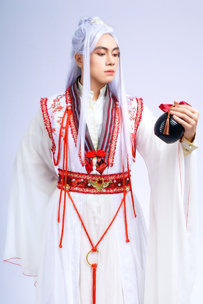 A person in traditional Asian attire with intricate red embroidery, showcasing cultural heritage.