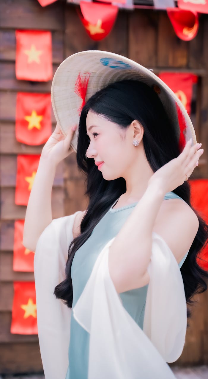 Elegant woman with long hair wearing a traditional Vietnamese hat and dress.